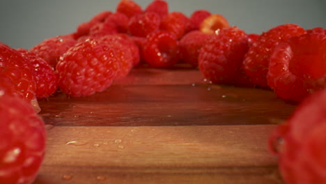 close up of fresh, juicy, red raspberries on a cutting board