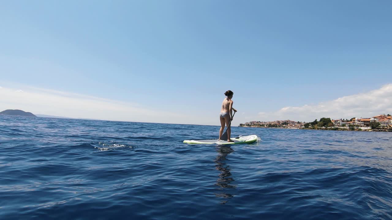 청록색 물 위에서 패들링을 하고 있는 젊은 여성