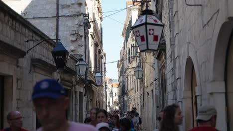 walking through the busy narrow street with a lot of tourists exploring the old town of dubrovnik in croatia with its traditional mediterranian stone houses on a sunny summer day