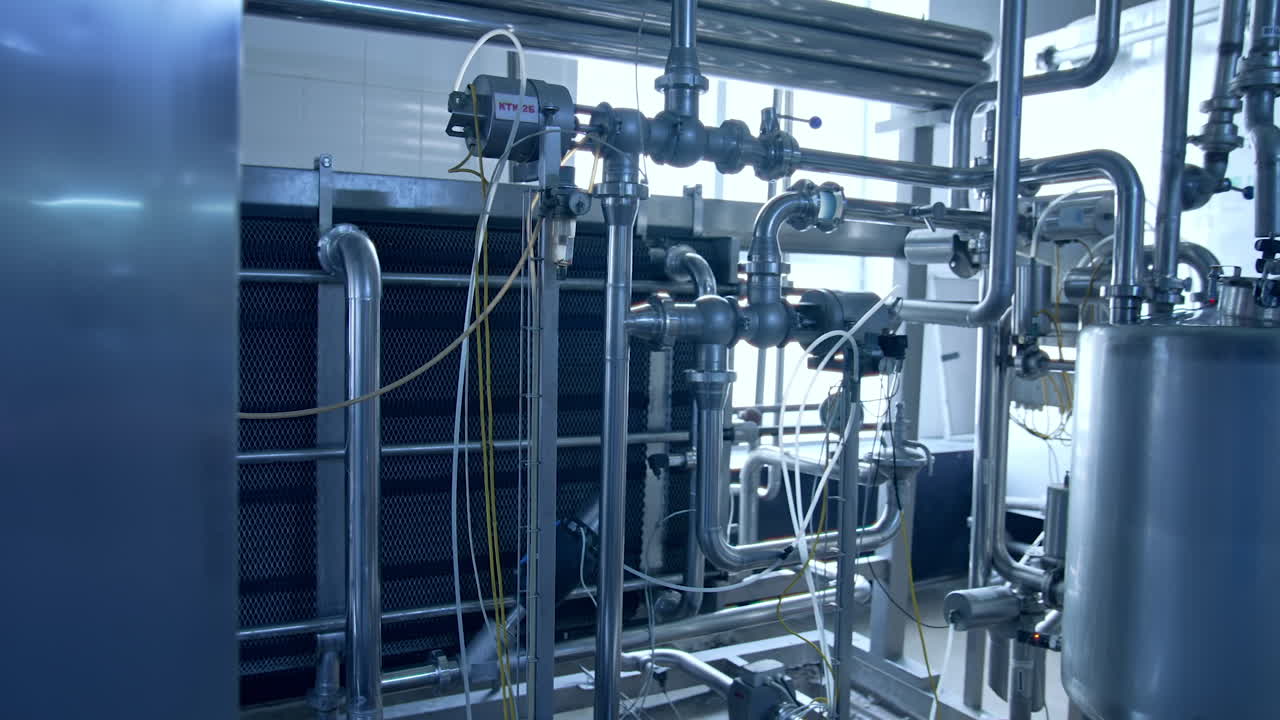 Stainless pipelines and tubes leading to the steel tanks. Metal box with sensor on it. Close up.