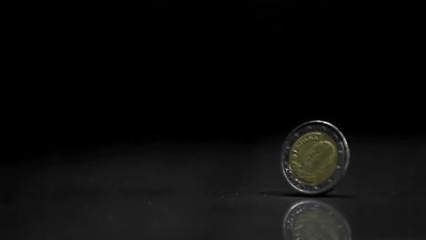 una moneda de dos euros que gira sobre un fondo negro