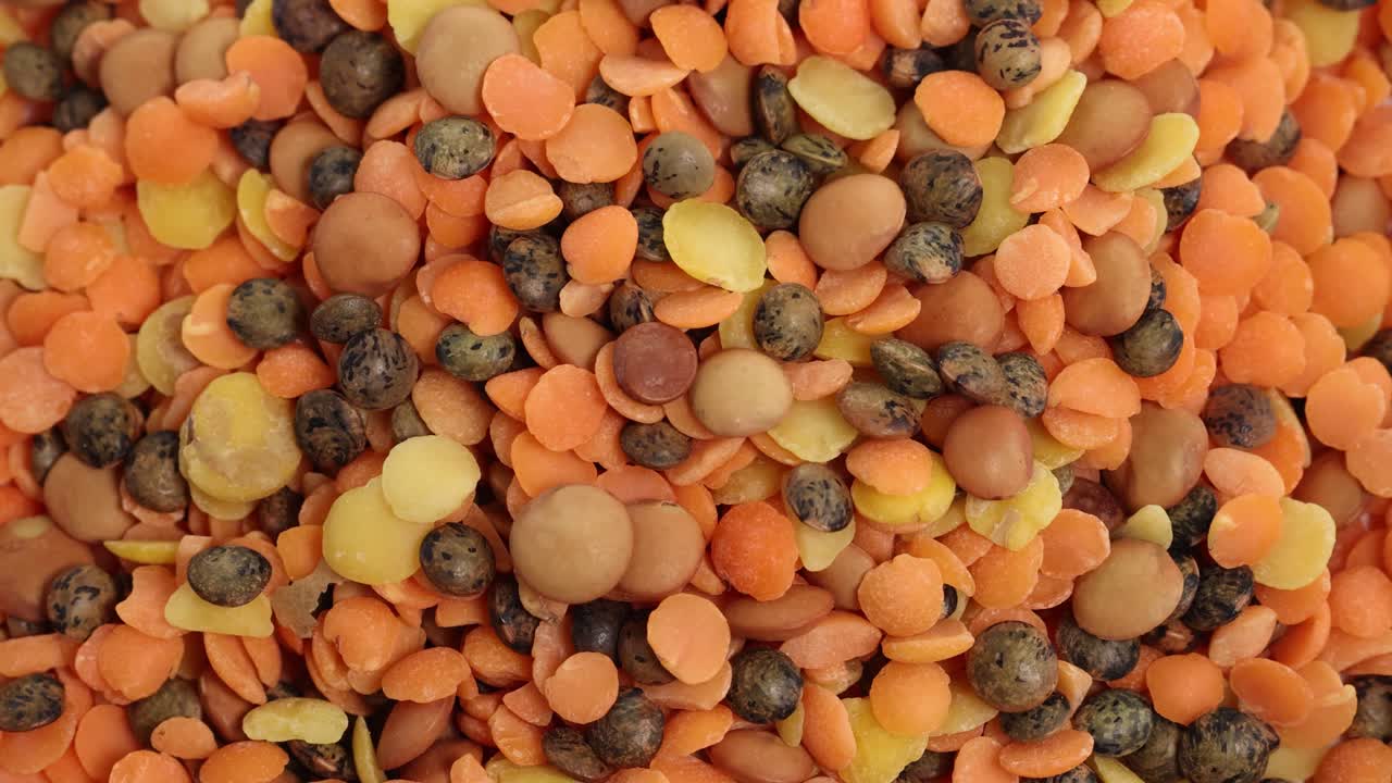 A vibrant mix of lentils and beans cascades down, creating a dynamic, colorful pattern in soft lighting