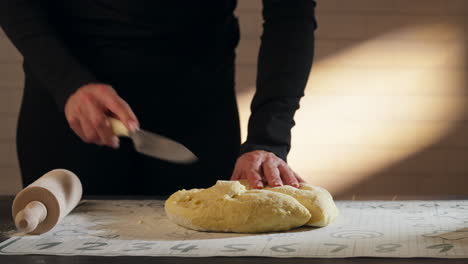 female hands cut dough with knife before kneading. closeup shot