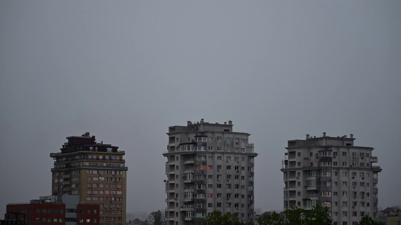 Timelapse de edifícios residenciais modernos erguendo-se em frente a nuvens em movimento, apresentando uma paisagem urbana tranquila com arquitetura urbana contemporânea.
