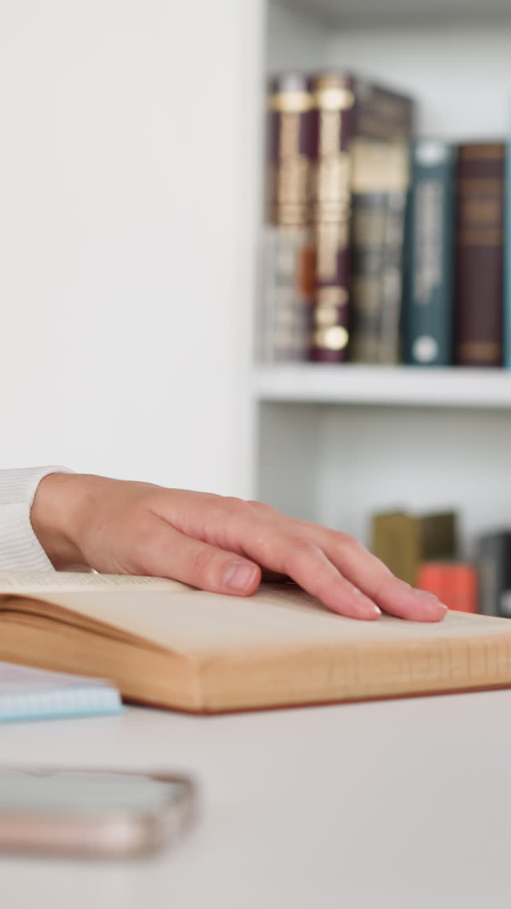 Female student rewrites information from book into notebook. Young woman prepares for seminar in university library. Obtaining higher education