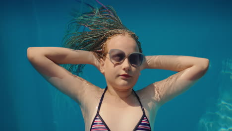 girl with afro pigtails, swims on an inflatable mattress in the pool, resting and enjoying the rest. top view