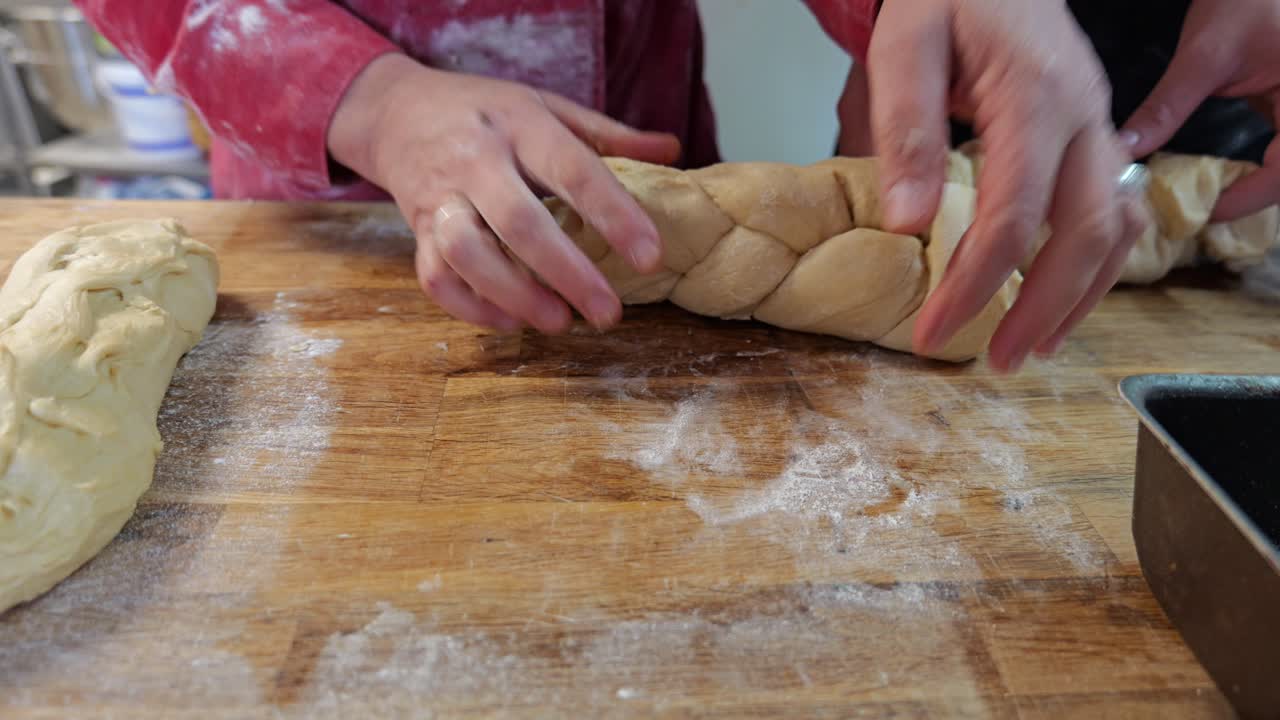 Baker braids pastry dough by hand before shaping and placing it in a mold
