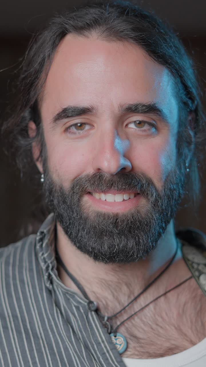 Close-up Portrait of a Smiling Man with a Beard and Long Hair