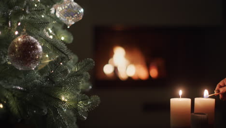 Una-Mano-Con-Una-Cerilla-Prende-Fuego-A-Las-Velas-Cerca-Del-árbol-De-Navidad-Y-La-Chimenea-Ardiendo-Al-Fondo.-Nochebuena