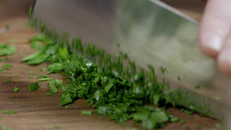 chef finely chop parsley with a kitchen ax knife to prepare chimichurri, argentinian sauce for barbecues