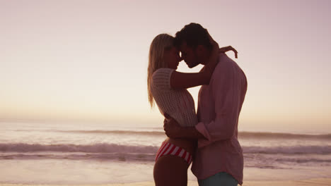 una pareja caucásica disfrutando del tiempo en la playa durante la puesta de sol