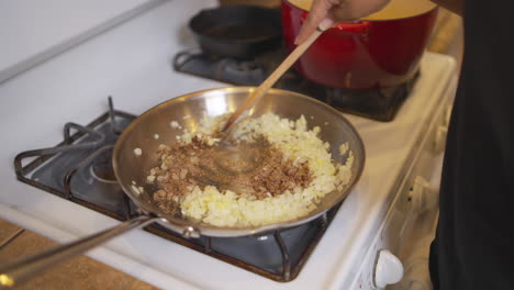 stirring meat and into a pan full of sautéed onions - slow motion isolated