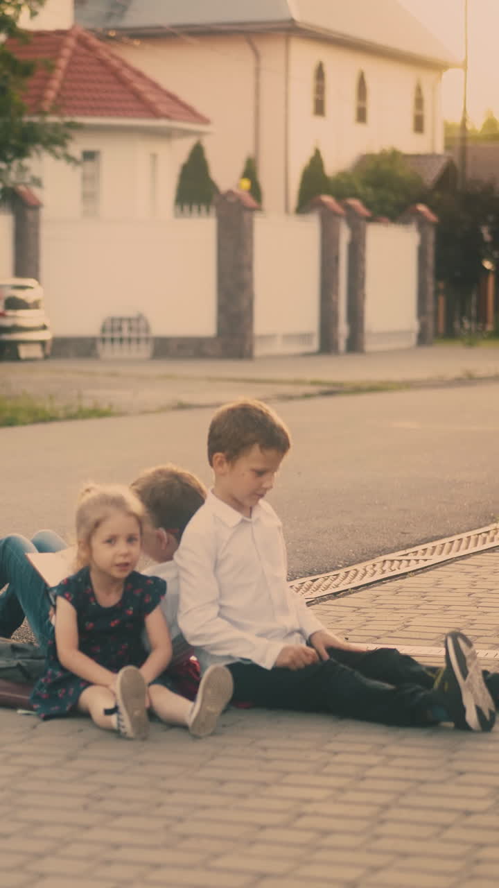 tired of studying children throw book on grey asphalt road lit by bright back sunlight in summer morning