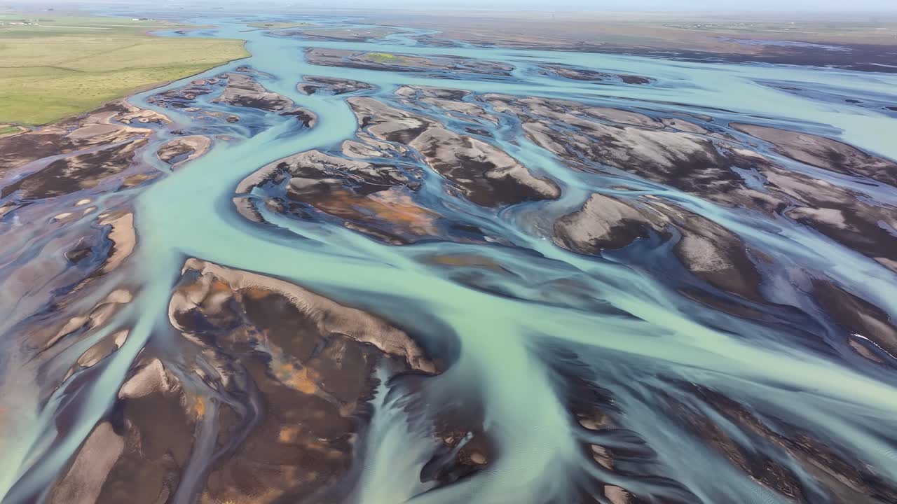 Soar above a braided river in Iceland with stunning drone footage revealing the twisting glacial channels, vibrant sediment colors, and breathtaking natural symmetry carved by melting glacial water