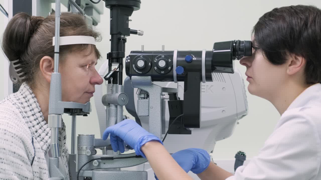 Woman doctor is viewing through ophthalmoscope in eyes of patient in ophthalmologic clinic. Professional inspection of vision