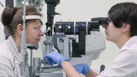 la mujer está viendo a través del oftalmoscopio en los ojos del paciente en la clínica oftalmológica. inspección profesional de la visión