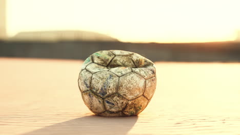 una pelota de fútbol vieja y desgastada al atardecer