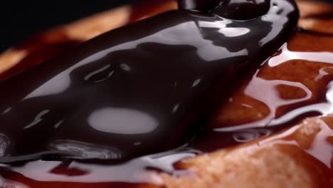 a smooth stream of glossy chocolate syrup flowing over the surface of a dessert