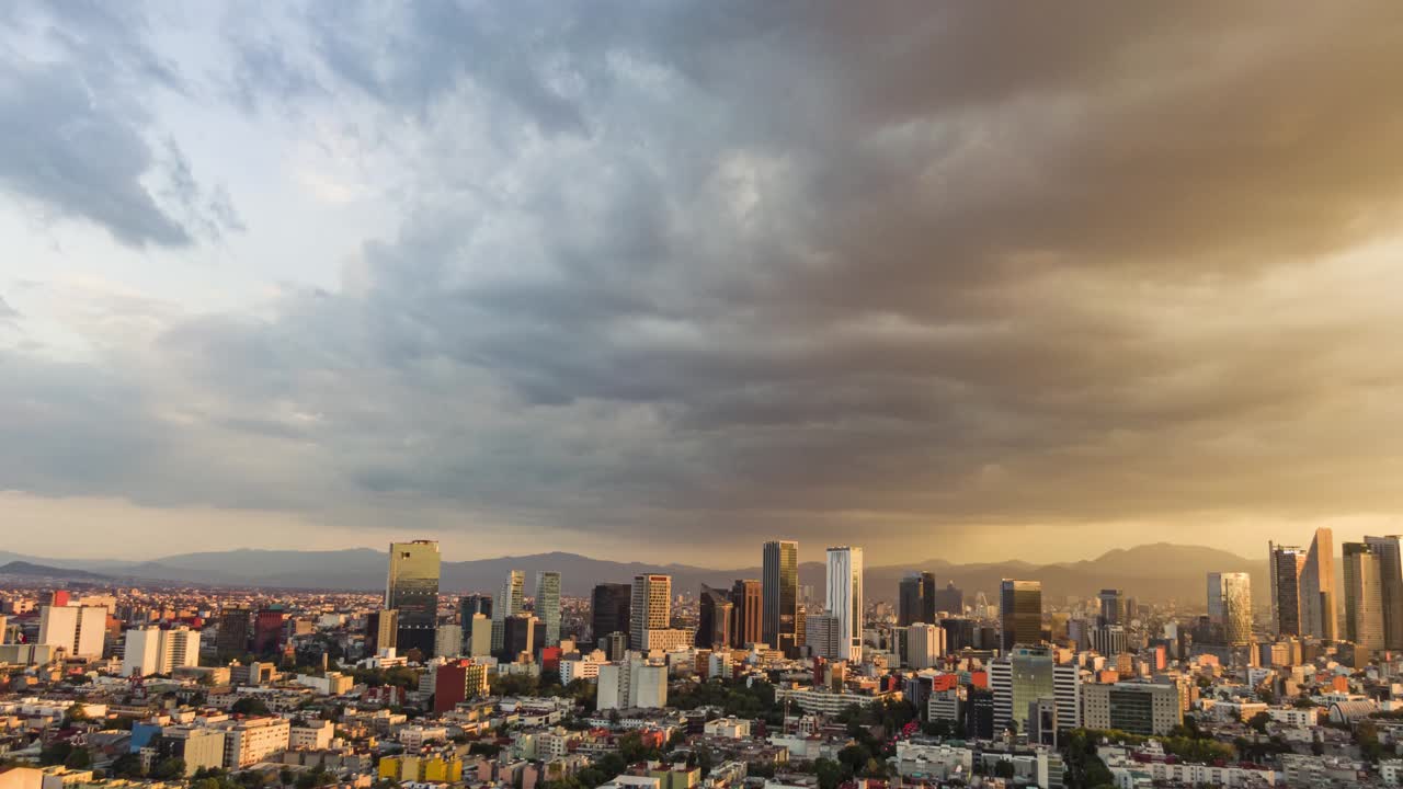 Hyperlapse top view flies over business, industrial and financial district of Mexico City, with skyscrapers of Paseo de la Reforma, on a dramatic cloudy day during the golden hour before sunset