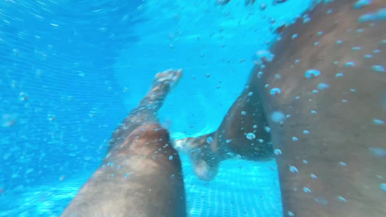 Ripresa subacquea in prima persona di gambe che scalciano in una piscina limpida. Perfetto per vlog di viaggi estivi, spot pubblicitari di resort e marketing di marchi di costumi da bagno