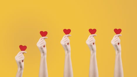 blogger mujer sostiene en la mano un pequeño corazón rojo en fondo amarillo naranja. como en la red social. día de san valentín, día internacional de la mujer, amor