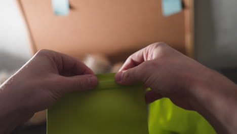 opening green packaging bag pov, preparing for marketplace shipment