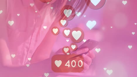 animation of changing numbers in speech bubble and heart icons over biracial woman using cellphone