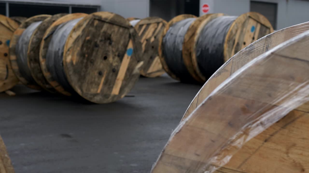 grandes bobinas de cable de madera en la planta de cables en el sitio. la bahía con un cable preparado para la carga en la fábrica de cables.