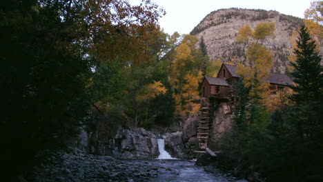 Bergbau-Mühlenhaus-Mit-Wasserfall,-Bach-Und-Fluss-Im-Herbst,-Herbstfarben,-Schieberegler-Am-Späten-Nachmittag-Rückwärts,-Filmisch-Nach-Rechts-Unten-Bei-Crystal-Mill-Marble,-Colorado