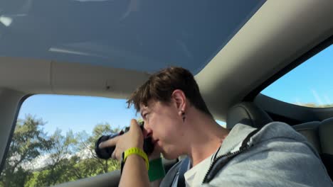 person in a car, taking pictures and sleeping