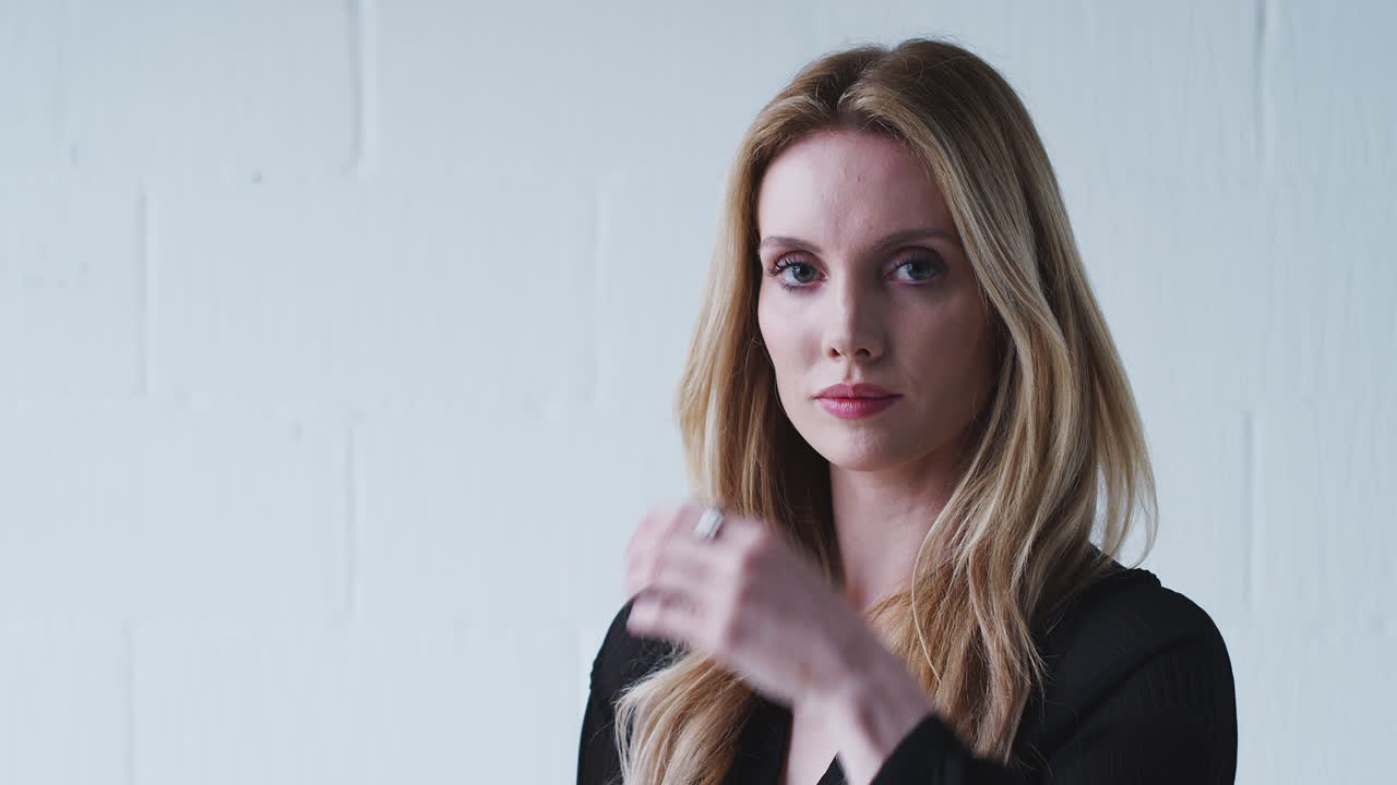 색 스튜디오 벽에 서 있는 미소 짓는 젊은 여성의 패션 초상화