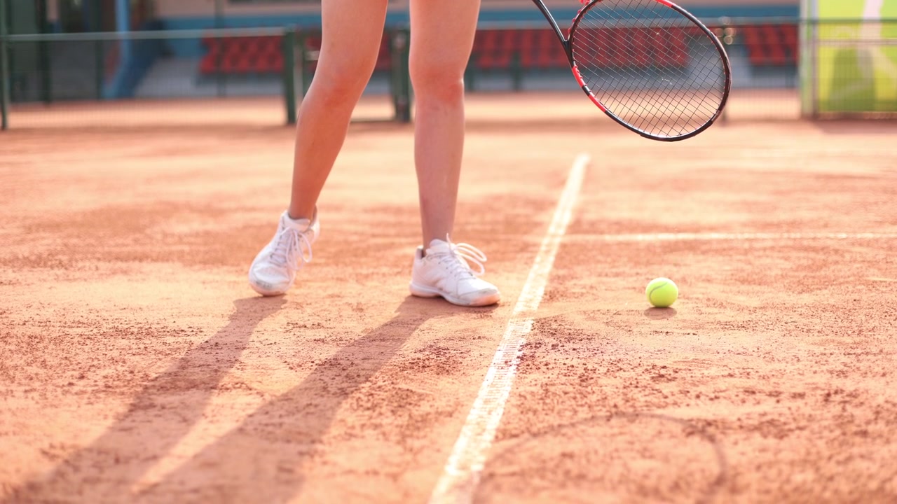 Tennisspiller spretter ballen på racketen på grusbane