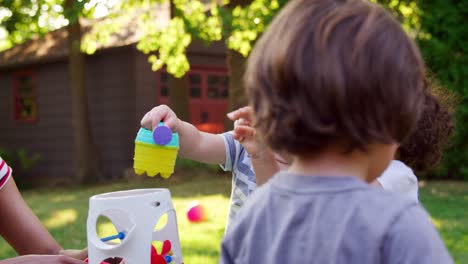 Madre-E-Hijos-Pequeños-Jugando-Con-Mesa-De-Agua-En-El-Jardín