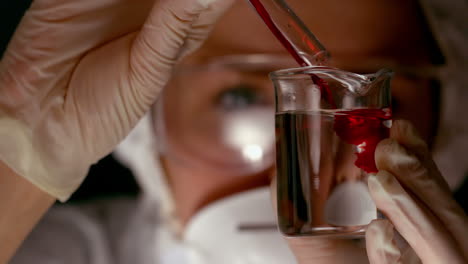 scientist pouring red chemical into beaker