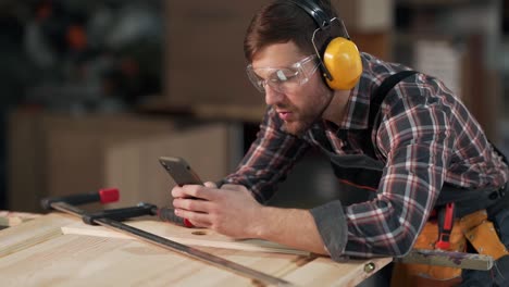 handsome man in work uniform takes pictures on the phone wooden products