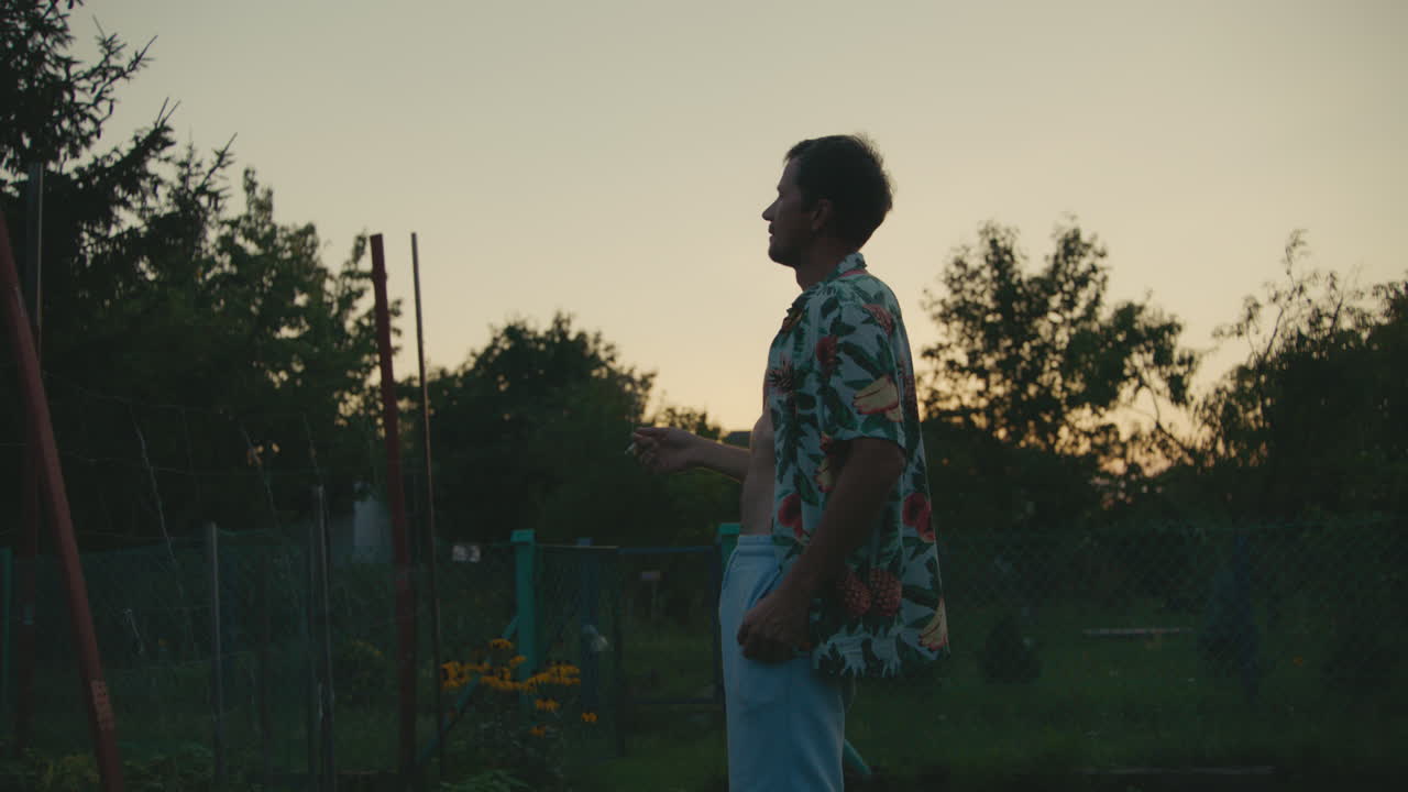 Homem fumando no jardim ao pôr do sol