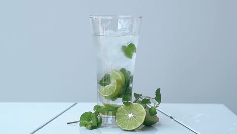 Glas-Mit-Kaltem-Mojito-Cocktail-Steht-Auf-Weißem-Tisch