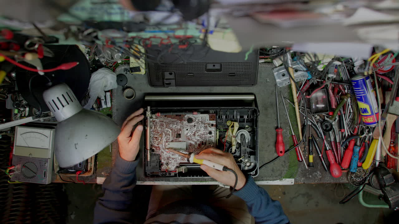 Senior technician electronics engineer repairs an old hi-fi receiver in the small workshop top-down shot