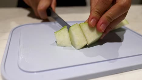 slicing a pear with a knife on a board