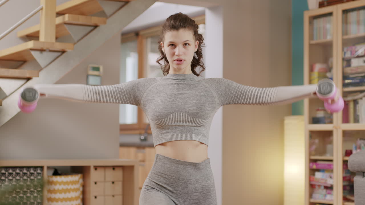 거실에서 아령으로 훈련하는 운동 백인 미녀, 집에서 아침 일상적인 피트니스