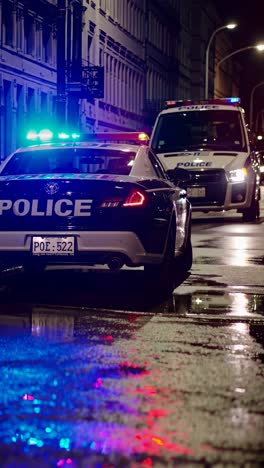 Nighttime urban scene with police cars on wet streets, captured from a low angle