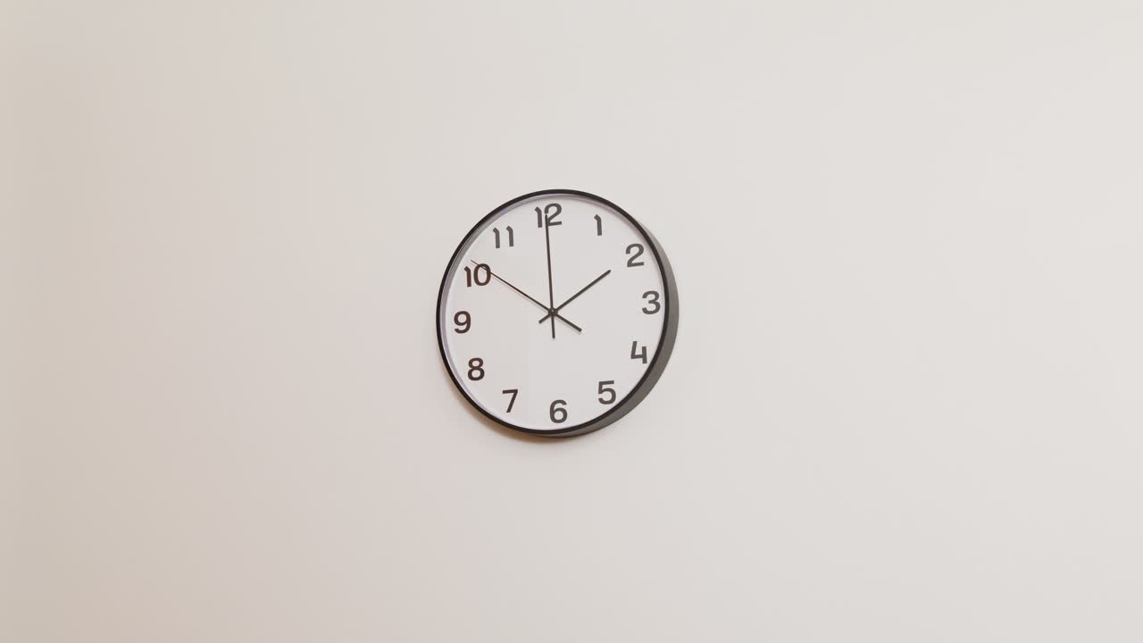 A minimalist office clock hanging on a white wall, showing the time as 2:00 in a clean and professional setting.