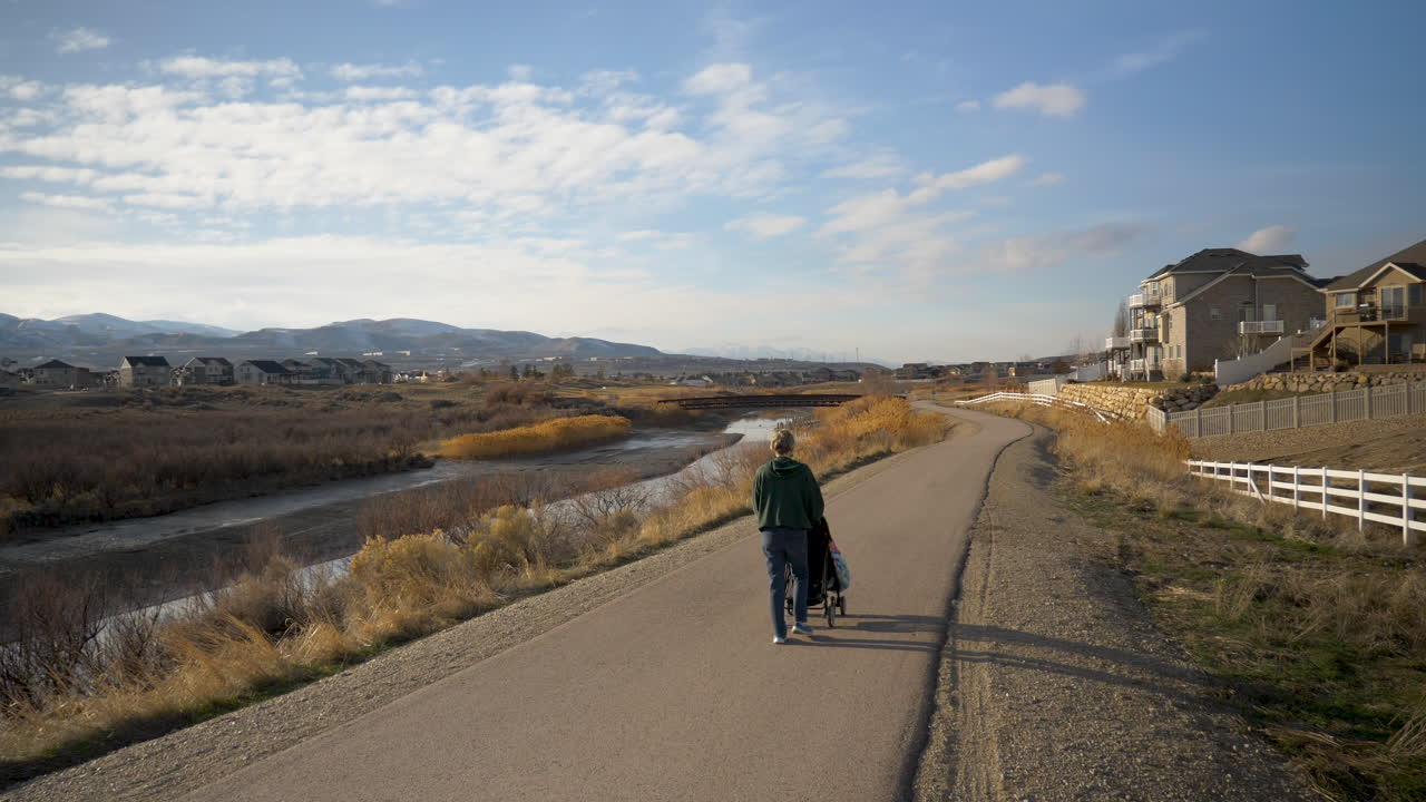포장된 오솔길 아래로 유모차에 아기를 밀어넣는 할머니 또는 어머니