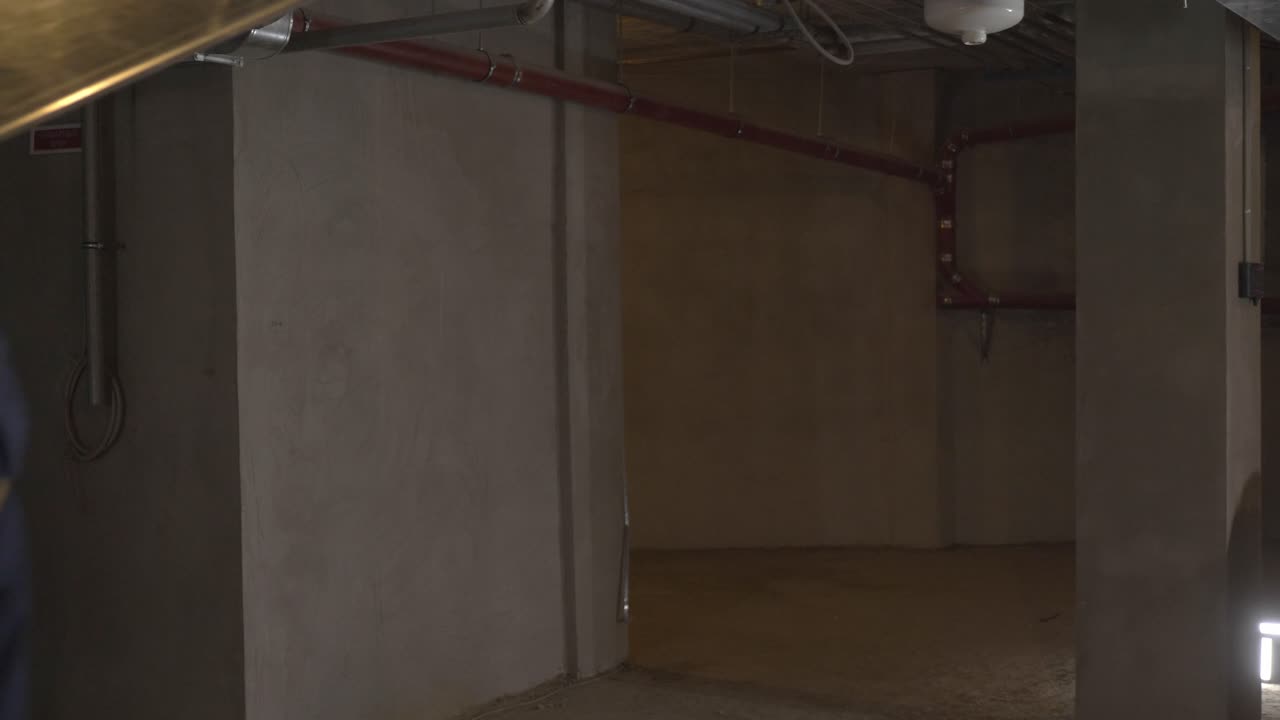 Construction worker carrying a metal duct in a basement