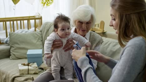 grandmother and mother opening presents for baby