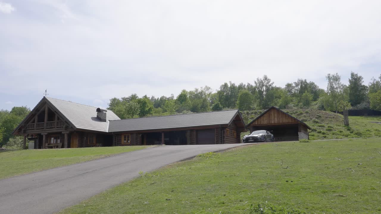 Car Driving Into a Garage Next to a Rustic Wooden Cabin