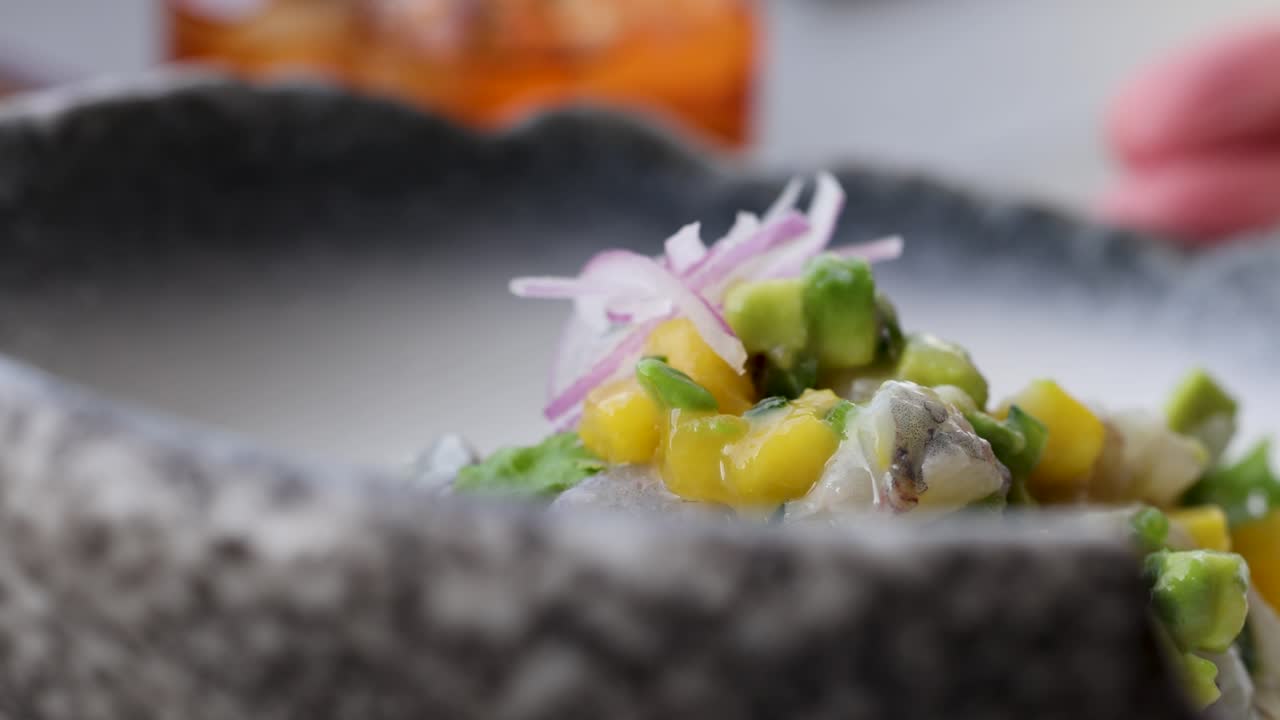 A vibrant Thai salad featuring squid, corn, and avocado in a textured bowl, captured in a close-up with soft lighting