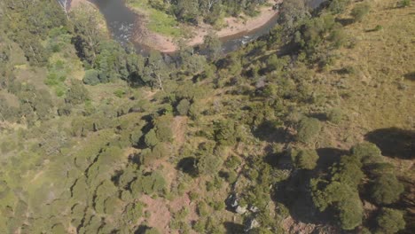 Toma-Aérea-Que-Revela-Un-Valle-Y-Un-Río-Que-Fluye-A-Través-Del-País-Alto-De-Australia