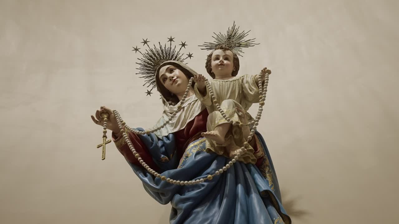 Vista detallada de una escultura de la Virgen María y el niño Jesús con un rosario dentro de una iglesia