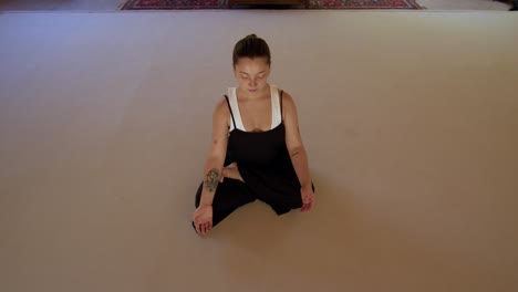 young woman practicing mindful yoga stretches in a peaceful, geometric studio outdoors, front view above in center